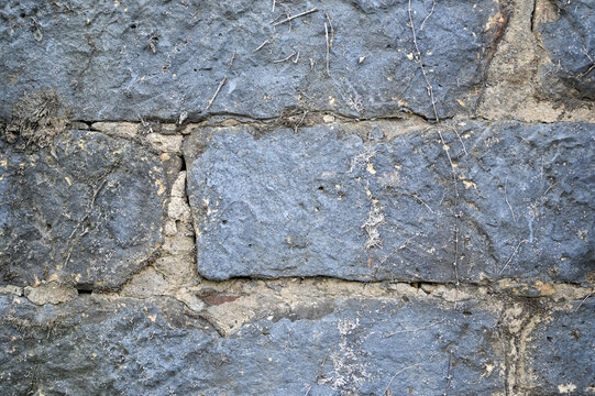 black cement block wall with crumbling cement and retro closup up texture of old paint and dirt