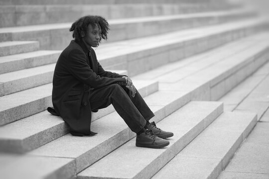 Solitary Young Man Sitting on Endless Stone Stairs in Monochrome Perspective with Copy Space