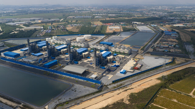 Aerial view of the Gulf Pluak Daeng Power Plant featuring blue industrial buildings and large water reservoirs in Map Yang Phon, Rayong, Thailand.