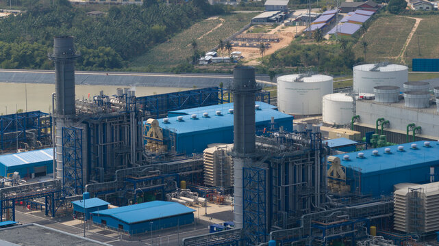 Aerial view of the Gulf PD Power Plant featuring tall chimneys, blue industrial buildings, and white storage tanks in Map Yang Phon, Rayong, Thailand.