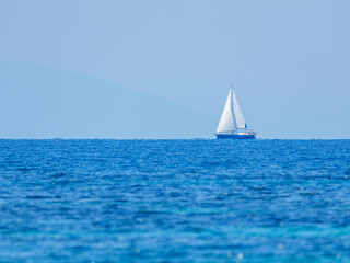 White Sailboat Sailing on Blue Sea Under Clear Sky © Ion B