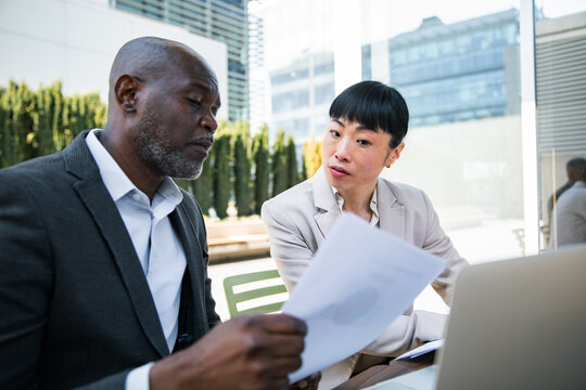 Two business professionals reviewing documents at outdoor office