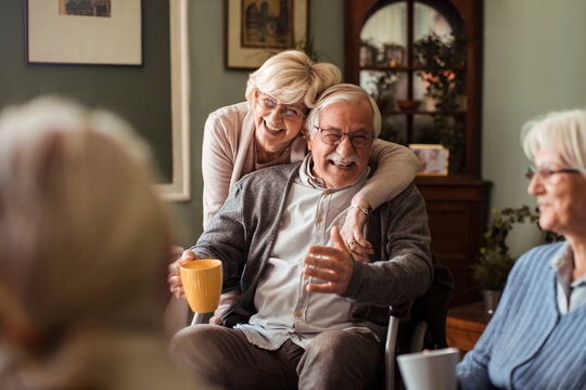 Smiling senior couple socializing with friends at home