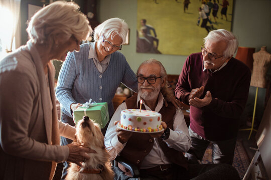 Senior friends celebrating birthday with cake at home