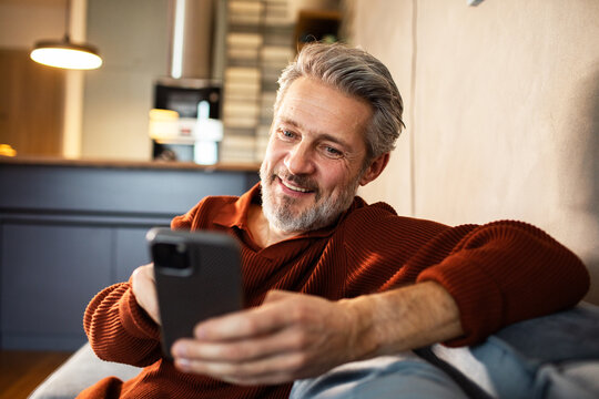 Smiling mature man using smartphone at home