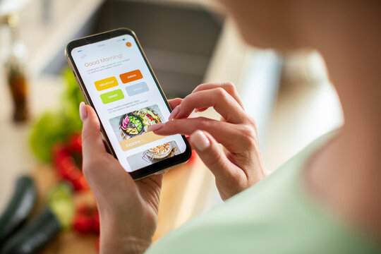 Person using recipe app on smartphone in home kitchen