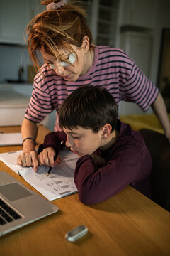 Parent helping child with homework at kitchen table at home