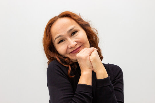 Mature woman with red hair looking with emotion and tenderness. Portrait of happy lady feeling touched and sentimental. Concept of sincere feelings, positive human emotion and affection.