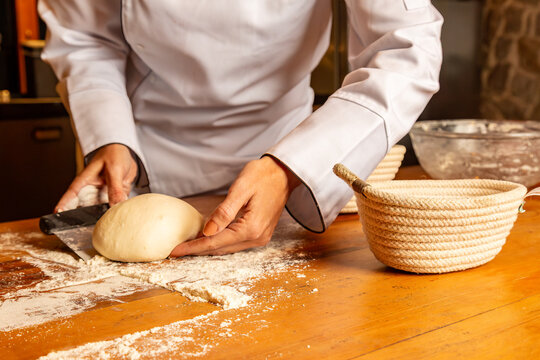 Chef cortando massa artesanal sobre bancada de madeira enfarinhada em cozinha
