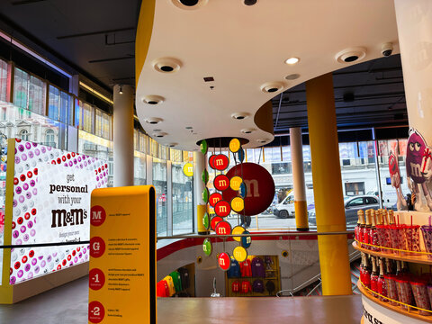 Inside the M and M's flagship store in London UK with colorful displays, branded merchandise, candy walls and shoppers exploring a vibrant modern retail interior