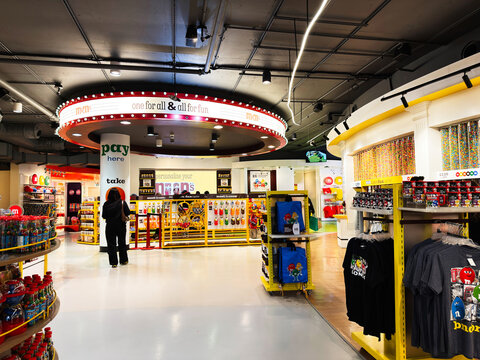 Interior of M and M's London store with colorful candy wall, shoppers and branded merchandise in a bright retail space in London, UK