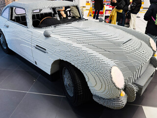 Naklejka premium Life size LEGO car sculpture of an Aston Martin displayed in a busy toy store in London, UK with shoppers taking photos and admiring the detailed brick model