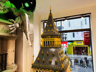 Naklejka premium Detailed LEGO tower model display in a London, UK toy store window with ornate gothic architecture and shoppers on the street below