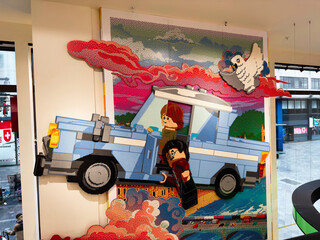 Naklejka premium Colorful LEGO mosaic of a flying car with wizard toy characters and owl installation in a London, UK store window