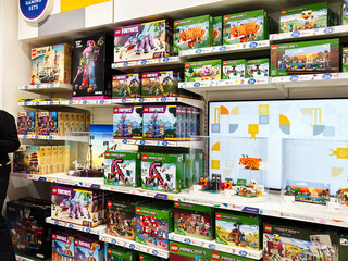 Fototapeta premium Lego store staff helping customers in a bright gaming sets aisle at a London, UK retail shop with Minecraft and Fortnite displays