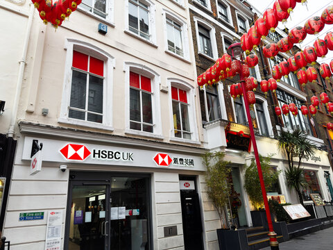 HSBC bank entrance beneath red Chinese lanterns in London UK Chinatown street with shoppers and traditional decorations
