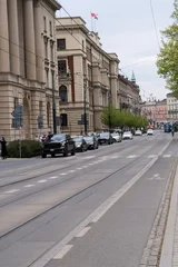 Street view in Krakow city center with historic architecture and tram tracks. People crossing the road next to classical buildings and moving traffic on a cloudy day in Poland. © Pat dream