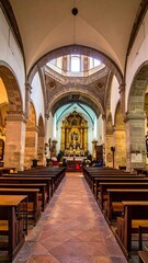 Fototapeta premium Interior church shot. Shows an altar at the far end, rows of wooden pews, stone arches, vaulted ceiling with a circular opening