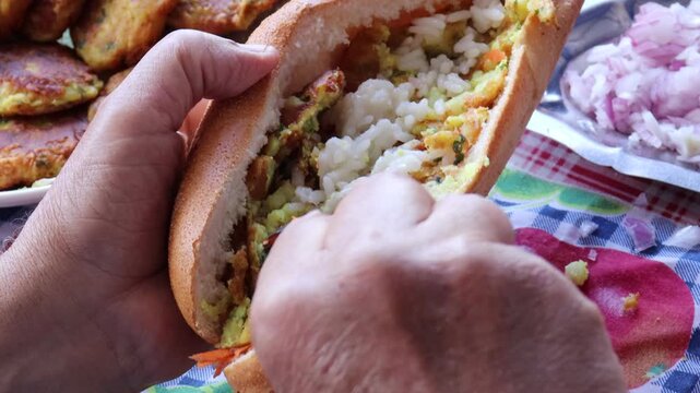 Stuffing Moroccan maakouda sandwich into baguette close-up