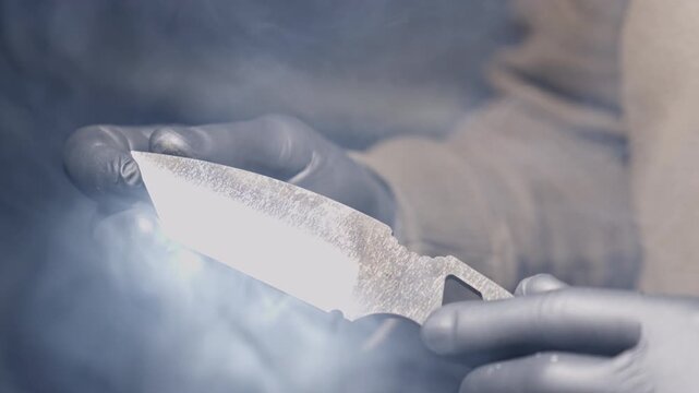Knife is held by blacksmith in workshop after sharpening