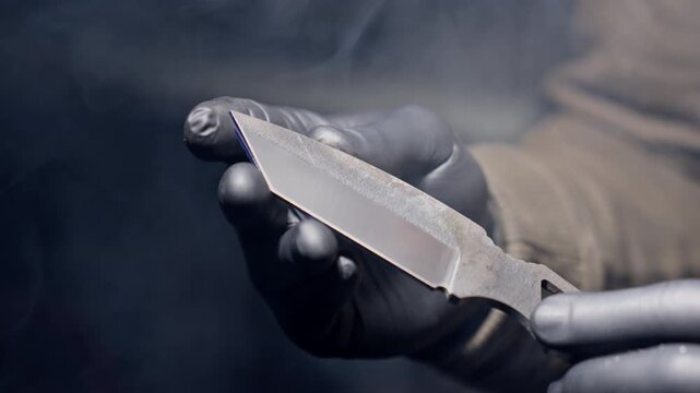 Knife is held by blacksmith in workshop after sharpening