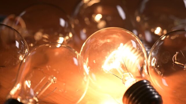 One glass incandescent bulb suddenly lights up among many turned off lamps. Bright lamp light in the dark symbolizing sudden insight the birth of an idea and intellectual breakthrough