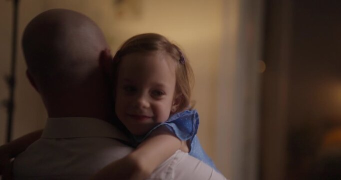 A joyful father and daughter share smiles and laughter in their cozy home, basking in the evening glow