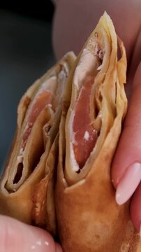 Thin tasty colorful pancakes. Close-up view of red, yellow and green cutaway rolled pancakes with cream cheese and salmon filling on a dish. 4K video. High quality 4k footage