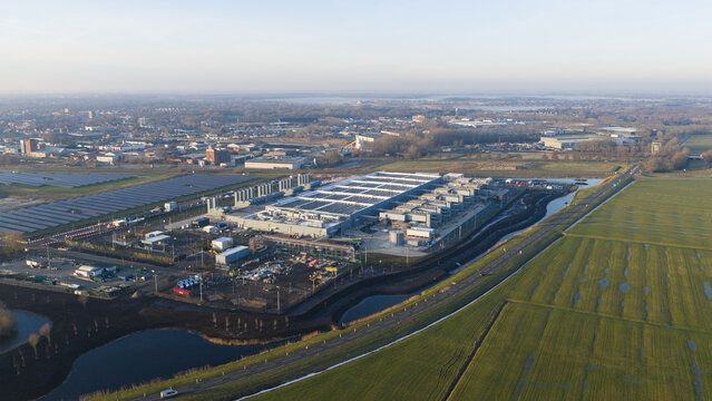 Aerial view of a large industrial facility and solar farm surrounded by green fields and canals in Winschoten, Groningen, Netherlands.