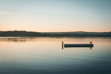 Sunset view of a floating pontoon on a peaceful mountain lake © Kristyna