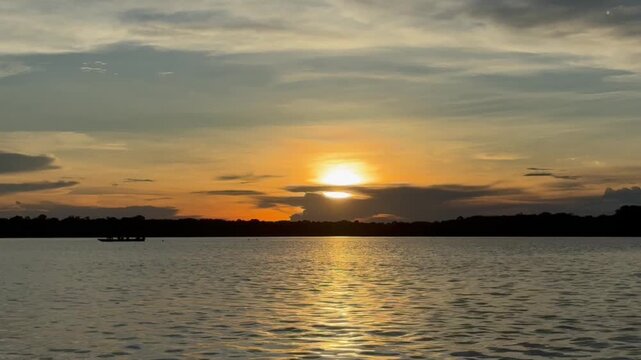 Cinematic Amazon River sunset with reflections on calm water filmed from a boat in Brazil