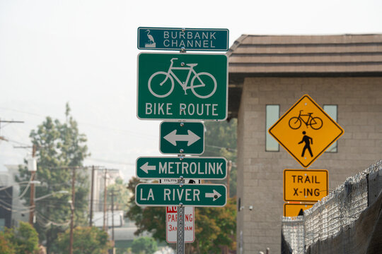 Street signs indicate bike route, Metrolink, and La River path directions