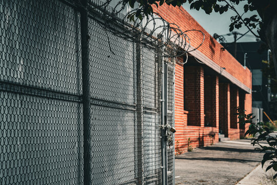 Chain link fence with razor wire and locked gate in front of brick building