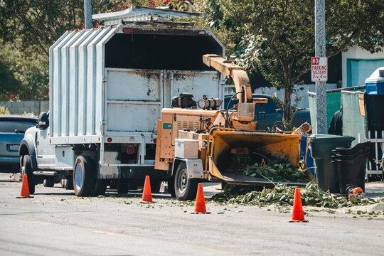 Heavy duty wood chipper machine attached to a truck for landscaping debris removal