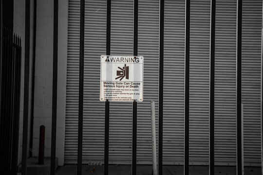 Warning sign on a metal gate about moving gate danger