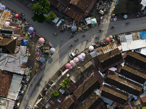 Aerial view of Pasar Kembang Klaten traditional market with colorful umbrellas, busy street traffic, and rustic rooftops Klaten, Central Java, Indonesia.