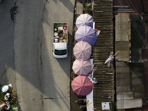Aerial view of Pasar Kembang Klaten traditional market with a white pickup truck filled with produce parked beside vibrant pink and purple umbrellas Klaten, Central Java, Indonesia.