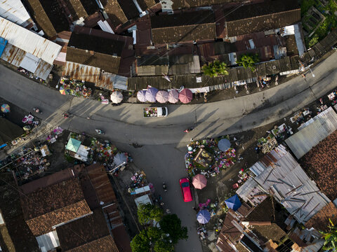 Aerial view of Pasar Kembang Klaten traditional market with colorful umbrellas, street intersection, and rooftops in Klaten, Central Java, Indonesia.