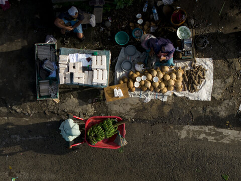 Aerial view of Pasar Kembang Klaten traditional market with vendors selling coconuts, bananas, and local produce on the street side in Klaten, Central Java, Indonesia.