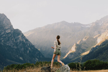 A woman stands on a rocky trail overlooking rugged mountains, enjoying outdoor life and fresh air. The scene conveys adventure, balance, resilience, and appreciation for nature. © SHOTPRIME STUDIO