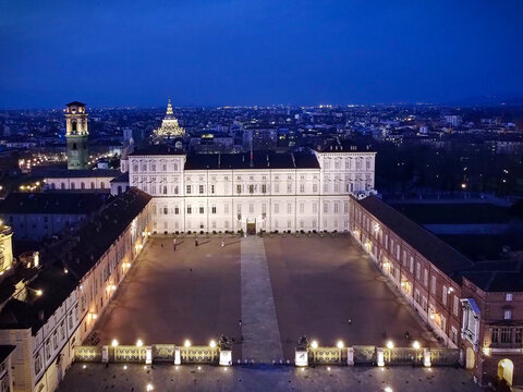 Aerial view of the illuminated Royal Palace of Turin and the city skyline at twilight with the Mole Antonelliana in the background in Turin, Piedmont, Italy.