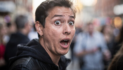 Fototapeta premium A shocked young person with wide eyes expressing surprise on a city street