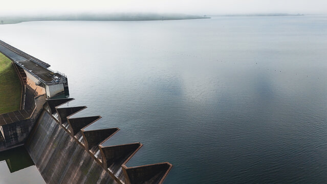 Aerial view of Midmar Dam featuring the concrete wall and calm water under a misty sky in Howick, KwaZulu-Natal, South Africa.