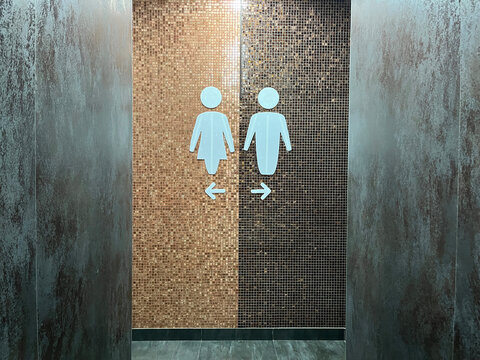 Restroom entrance featuring gender signs on tiled wall