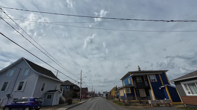 Dashcam footage driving through the charming coastal village of Baie-des-Sables on Quebec&rsquo;s Gasp&eacute; Peninsula beneath a dramatic grey sky and colorful seaside homes.