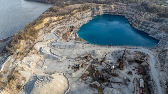Aerial view of Tomkins Cove quarry featuring a deep blue lake, industrial machinery, and gravel piles near the Hudson River in Stony Point, New York, United States.