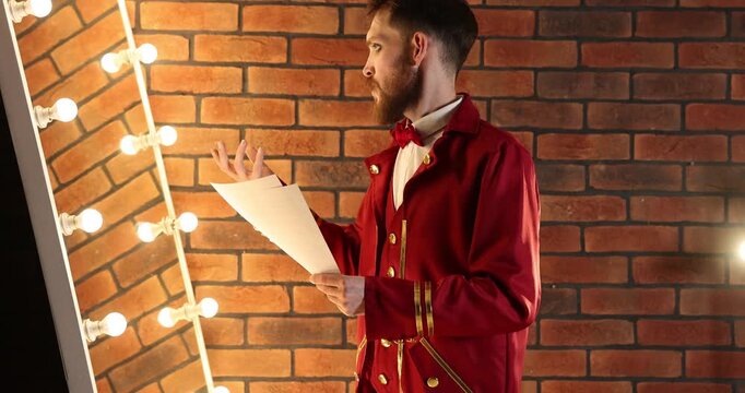 Actor with script rehearsing his lines near mirror in dressing room, camera moving down