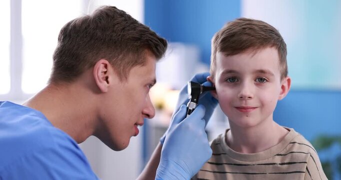 Hearing test. Doctor examining boy's ear with otoscope in clinic. Camera moving forward