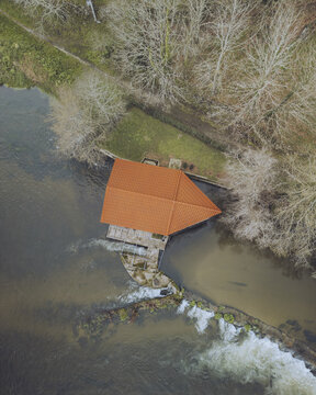 Aerial view of watermill house by the beautiful Lima River surrounded by serene trees and lush greenery, Jolda, Viana do Castelo, Portugal.