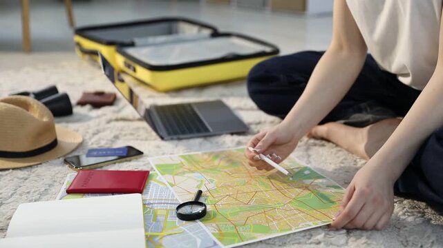 Planning trip. Woman looking at map on floor indoors, closeup